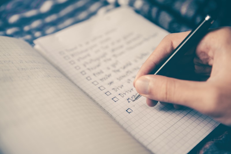A weekly paper planner open on a desk with a few time slots marked in pencil.